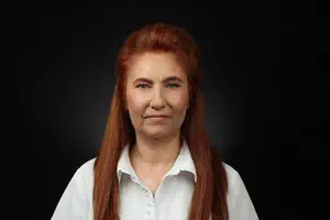 Служителка с дълга червена коса и естествен грим в бяла риза